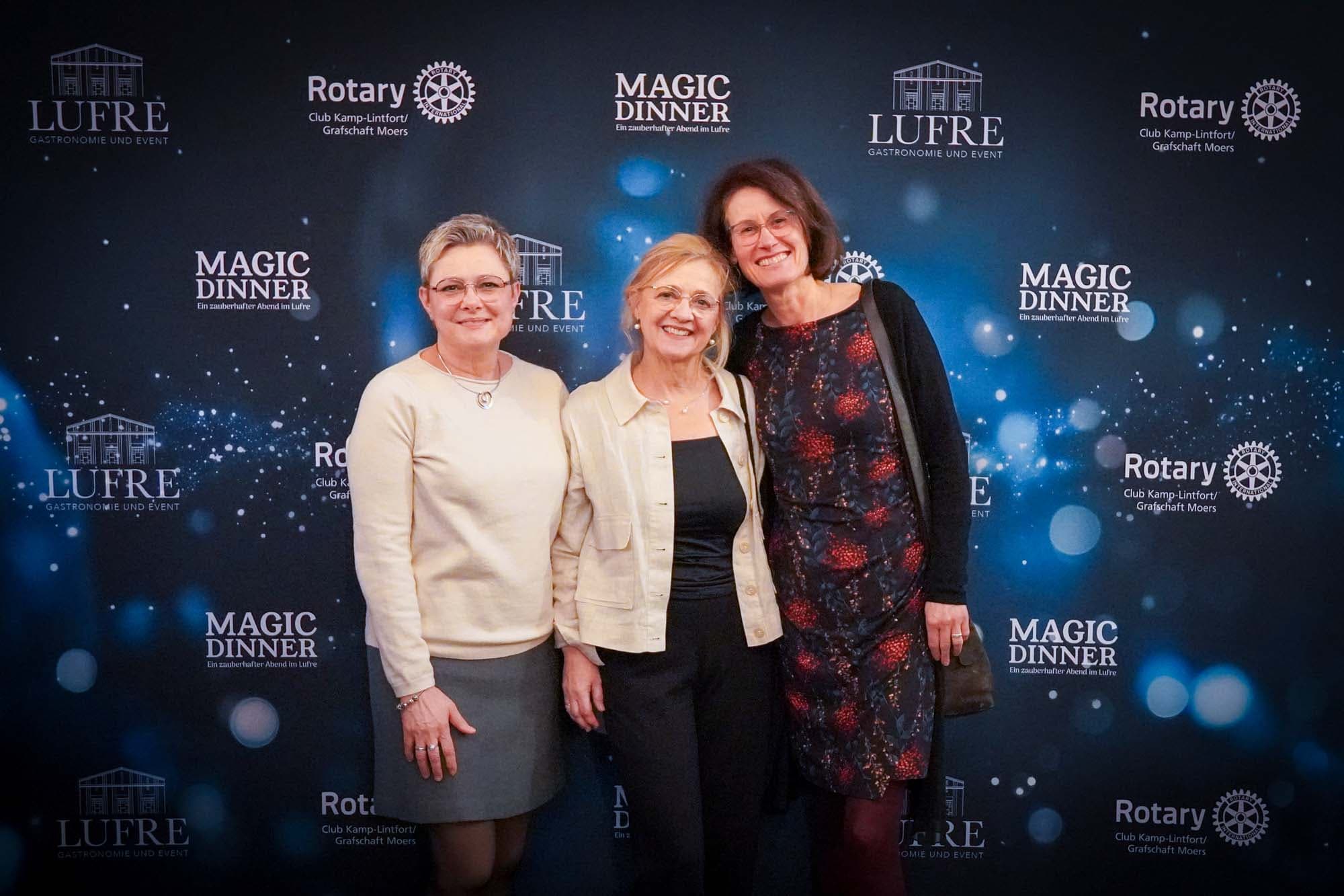 Drei Frauen posieren lächelnd vor der Pressewand, die mittlere in hellem Blazer wird von den beiden anderen eingerahmt.